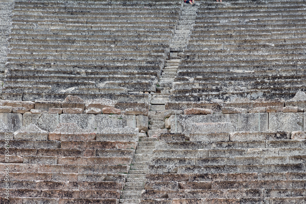 Stairs of the ancient theatre of Epidaurus in the Epidaurus town, on Peloponnesus peninsula, Greece. The theater was dedicated to the ancient Greek God of medicine, Asclepius. Stairs closeup. Stairs of the ancient theatre of Epidaurus in the Epidaurus town, on Peloponnesus peninsula, Greece. The theater was dedicated to the ancient Greek God of medicine, Asclepius. Stairs closeup.