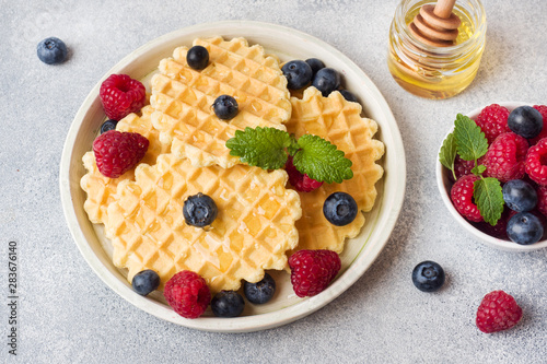 Corrugated waffle cookies with fresh raspberries and blueberries on a concrete background. Copy space.