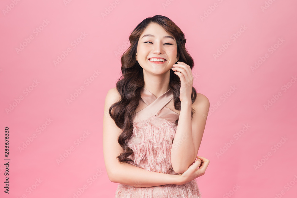 Image of charming woman 20s wearing dress smiling and standing isolated over pink background Image of charming woman 20s wearing dress smiling and standing isolated over pink background