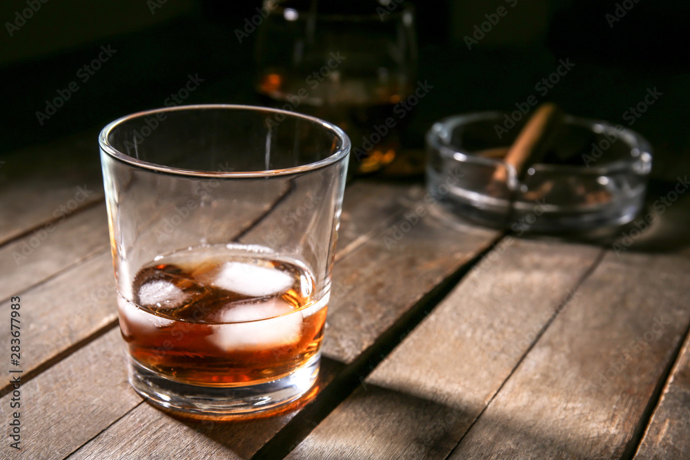 Glass of cold whiskey with ice on wooden table Glass of cold whiskey with ice on wooden table