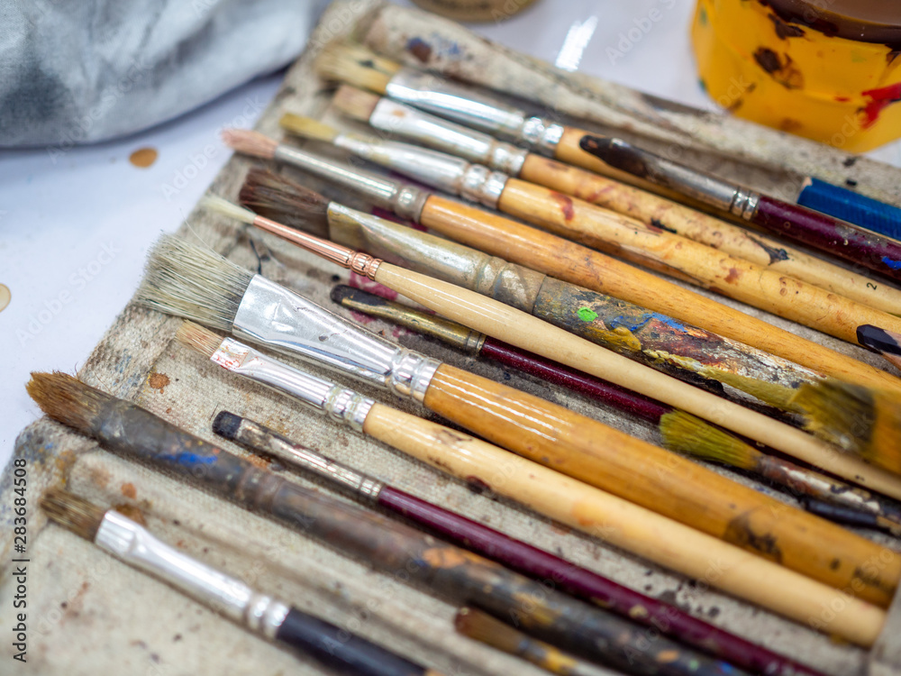 Fototapeta premium Artist paint brush set. Close-up many artist tools in calico paint brush holder.