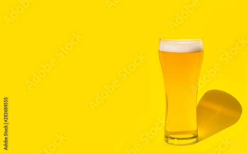 Beer. Cold Craft light Beer in a glass with water drops. Pint of Beer close up isolated on yellow color background with copy space.Oktoberfest concept.