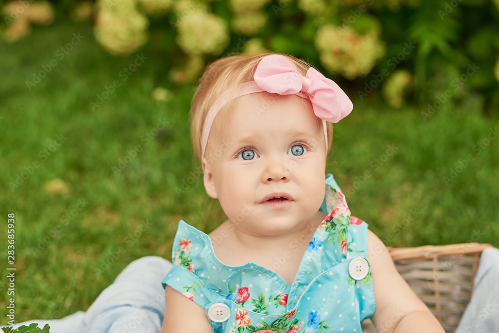 Children Protection Day, baby girl in the park sits in a basket on a summer picnic Children Protection Day, baby girl in the park sits in a basket on a summer picnic