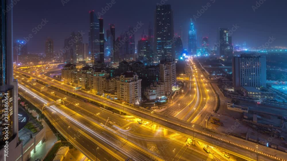 Dubai downtown skyline night to day transition aerial timelapse with traffic on highway, UAE. Top view from rooftop of skyscraper with modern towers near intersection of Al Saada street and Financial Dubai downtown skyline night to day transition aerial timelapse with traffic on highway, UAE. Top view from rooftop of skyscraper with modern towers near intersection of Al Saada street and Financial