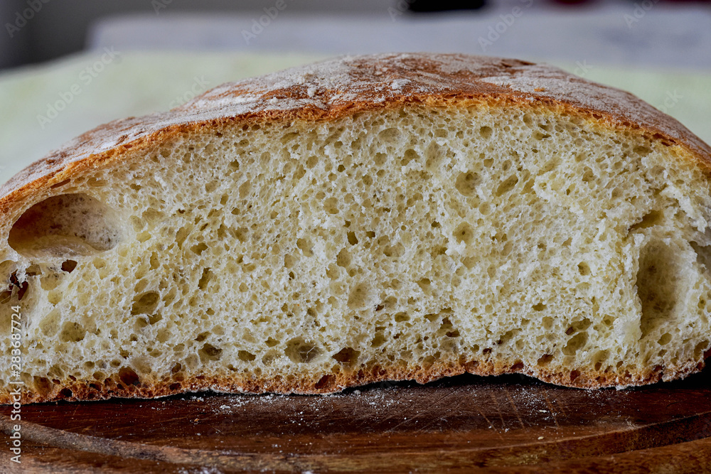 Closeup of freshly baked bread in rustic style/ Fresh round bread with a beautiful crust lies on a wooden board/ Homemade bread 