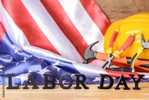 USA flag, hardhat, tools and text LABOR DAY on wooden table