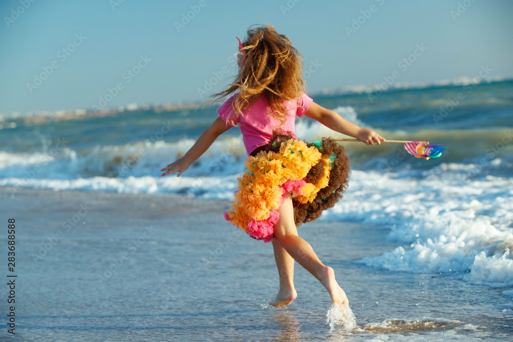 Naklejka premium Little girl at the sea. A child runs on the waves. 