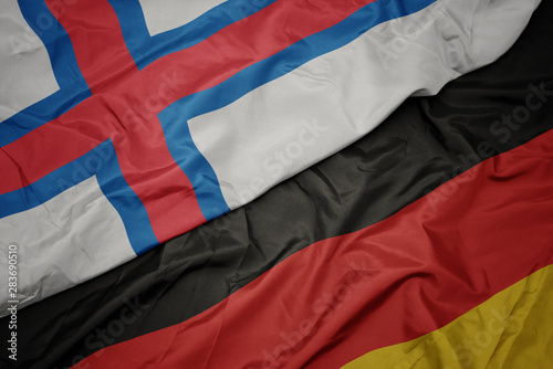 waving colorful flag of germany and national flag of faroe islands.