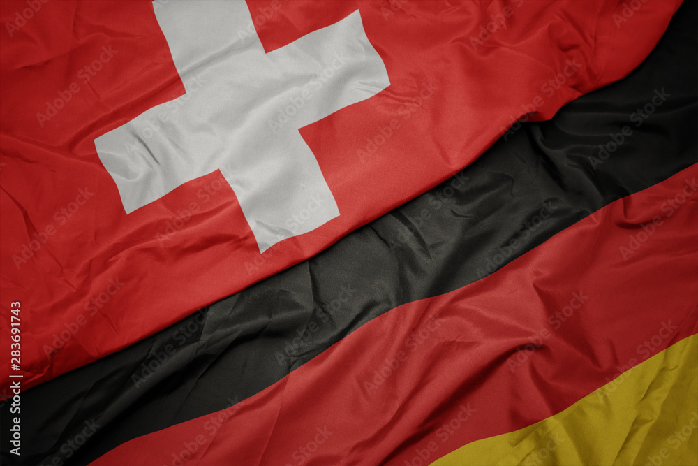 waving colorful flag of germany and national flag of switzerland. waving colorful flag of germany and national flag of switzerland.
