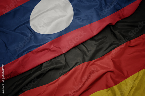 waving colorful flag of germany and national flag of laos.