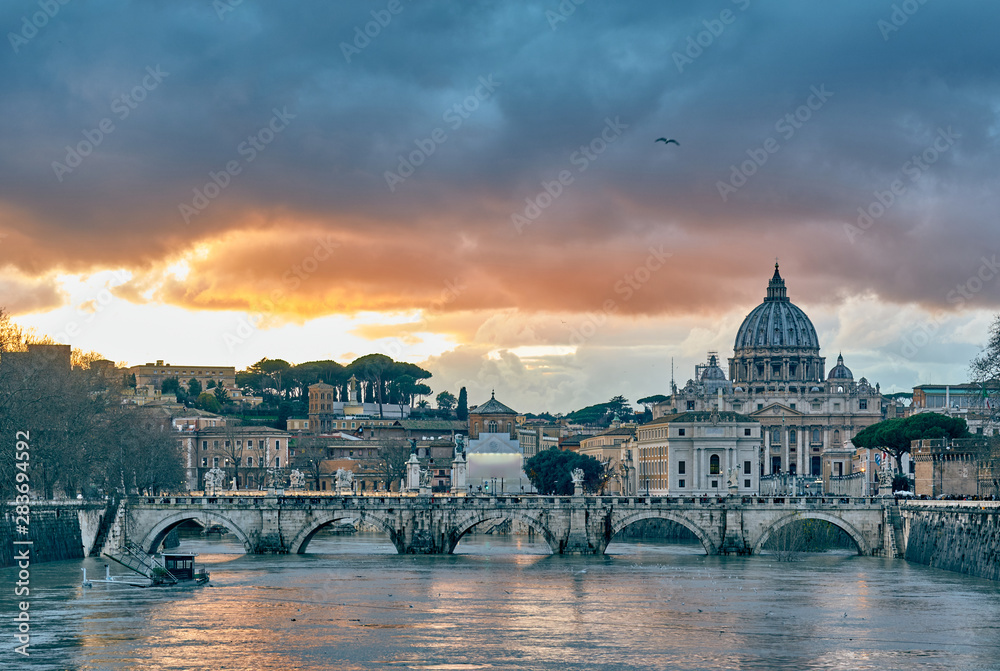 St. Peter's cathedral and Tiber river with high water at evening with dramatic sunset sky. Saint Peter Basilica in Vatican city with Saint Angelo Bridge in Rome, Italy