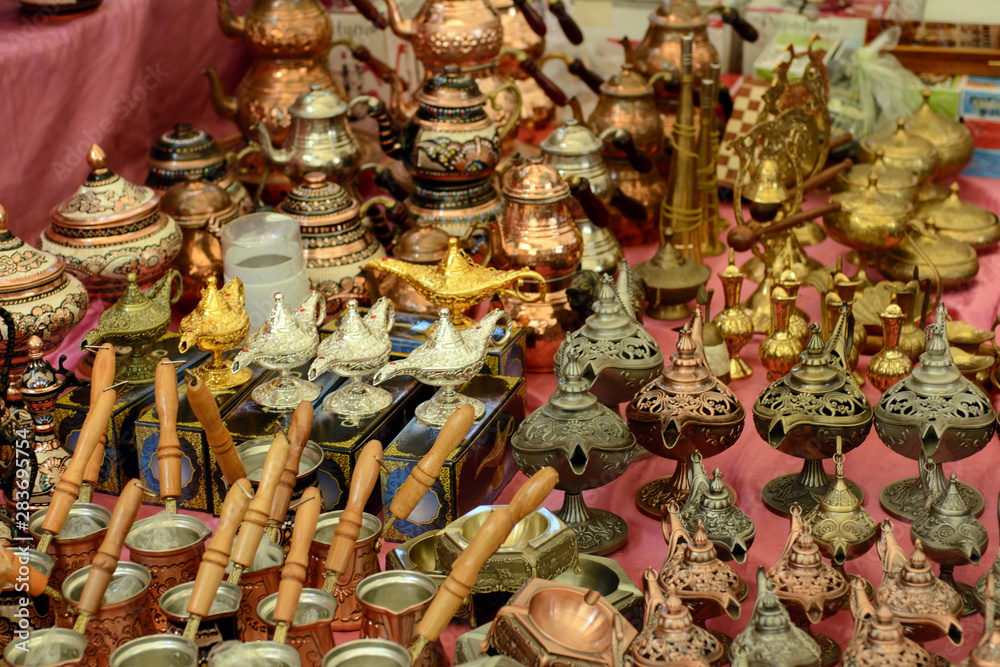 Naklejka premium Turkish copper coffee pots and cups with ornaments on a counter in a Turkish bazaar