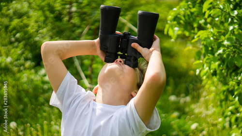 boy looks for wildlife through binoculars in the park explore the world.