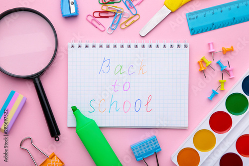 Inscription Back To School with school supplies on pink background