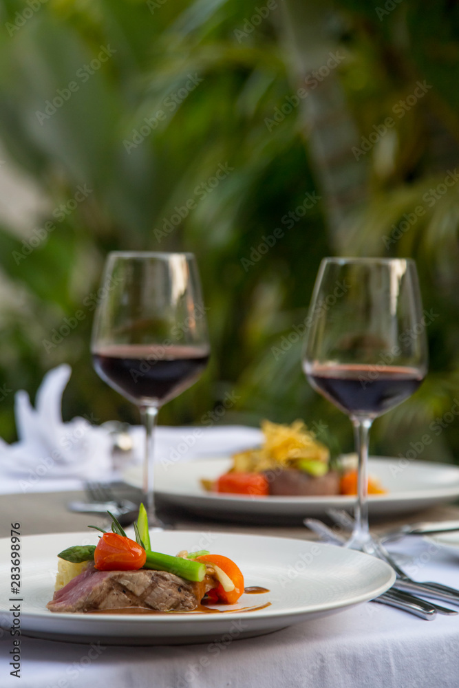 Beefsteak with steamed vegetables and glasses of red wine served on the table, Romantic dinner outdoor Beefsteak with steamed vegetables and glasses of red wine served on the table, Romantic dinner outdoor