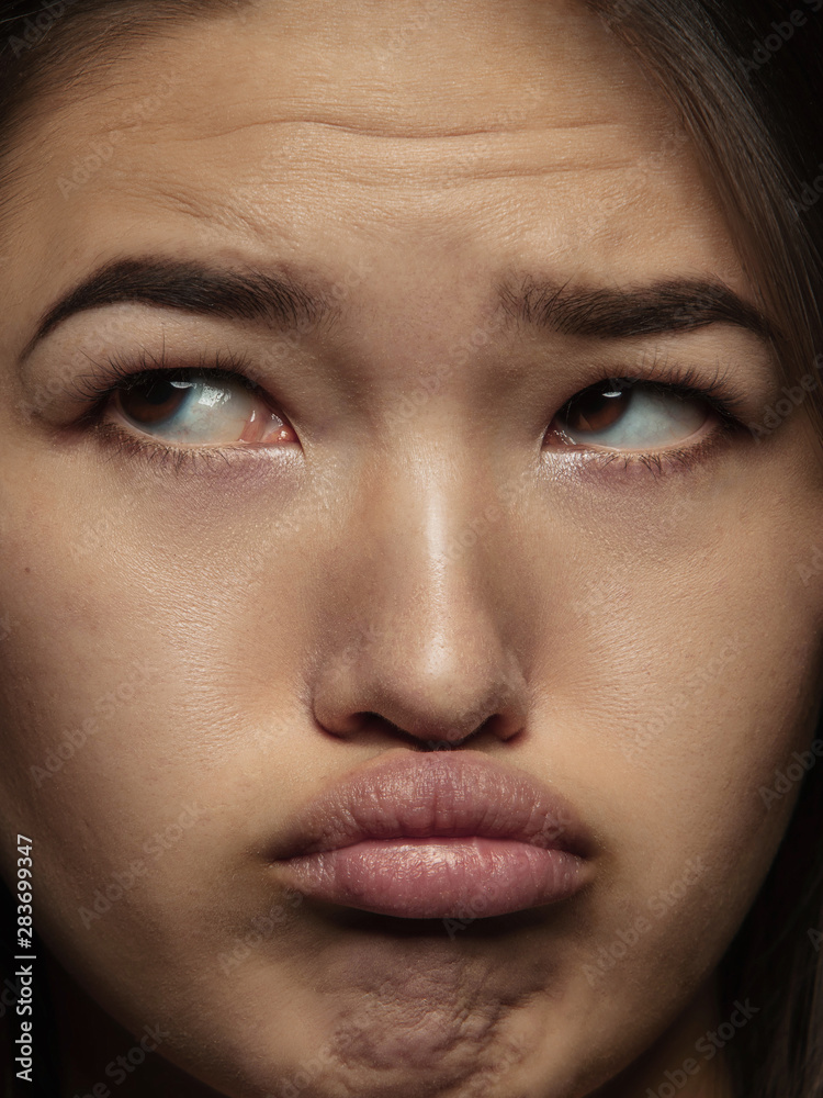Fototapeta premium Close up portrait of young and emotional chinese woman. Highly detail photoshot of female model with well-kept skin and bright facial expression. Concept of human emotions. Looks sad, offended.