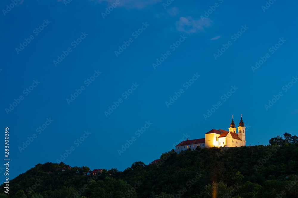 Tihany Benedictine abbey in yellow light at the blue hour in Tihany, Hungary