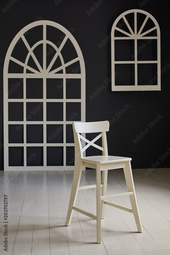 White chair on dark background.The wall is decorated with details in the form of arched doors and arched Windows. White chair on dark background.The wall is decorated with details in the form of arched doors and arched Windows.
