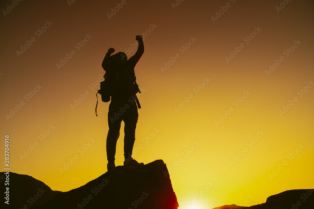 Man standing on edge of mountain feeling victorious with arms up in the air. Victory. Success, life goals Man standing on edge of mountain feeling victorious with arms up in the air. Victory. Success, life goals