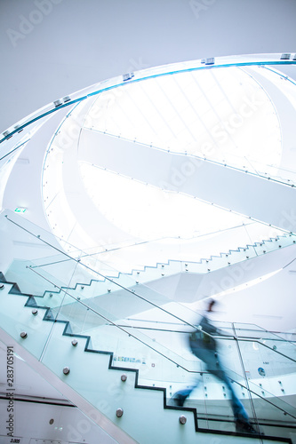 People inside a modern building walking up the stairs (color toned image; motion blurred image)