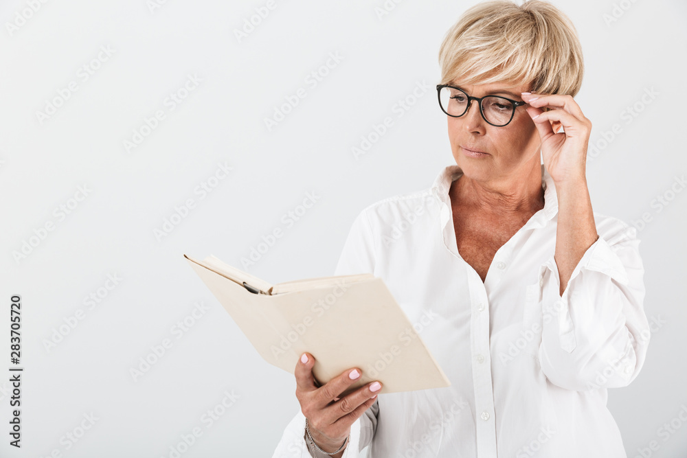 Portrait of concentrated adult woman wearing eyeglasses reading book Portrait of concentrated adult woman wearing eyeglasses reading book