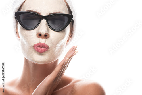 front view of nude woman in sunglasses with facial mask making kissing face expression isolated on white