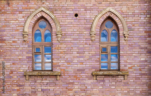 Brick wall with two windows in the Gothic style. Gothic style in architecture
