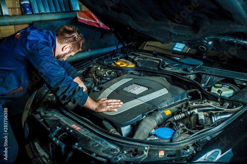 Mechanic working in car motor. Auto repair, Service center. Mechanic with wrench working and repair car engine in car service centre.