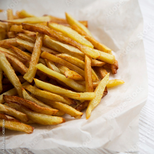 French fries on a white wooden surface, side view. Close-up.