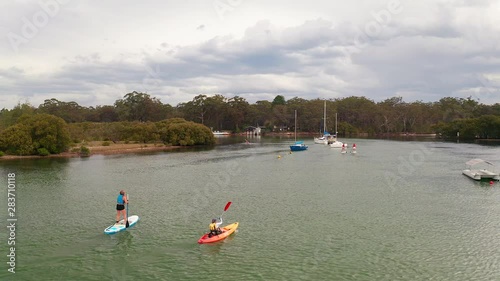 Aerial circling shot of friends kayaking and paddling over Currambene Creek, Australia. photo