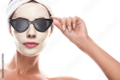 front view of woman in sunglasses and cosmetic hair band with facial mask isolated on white