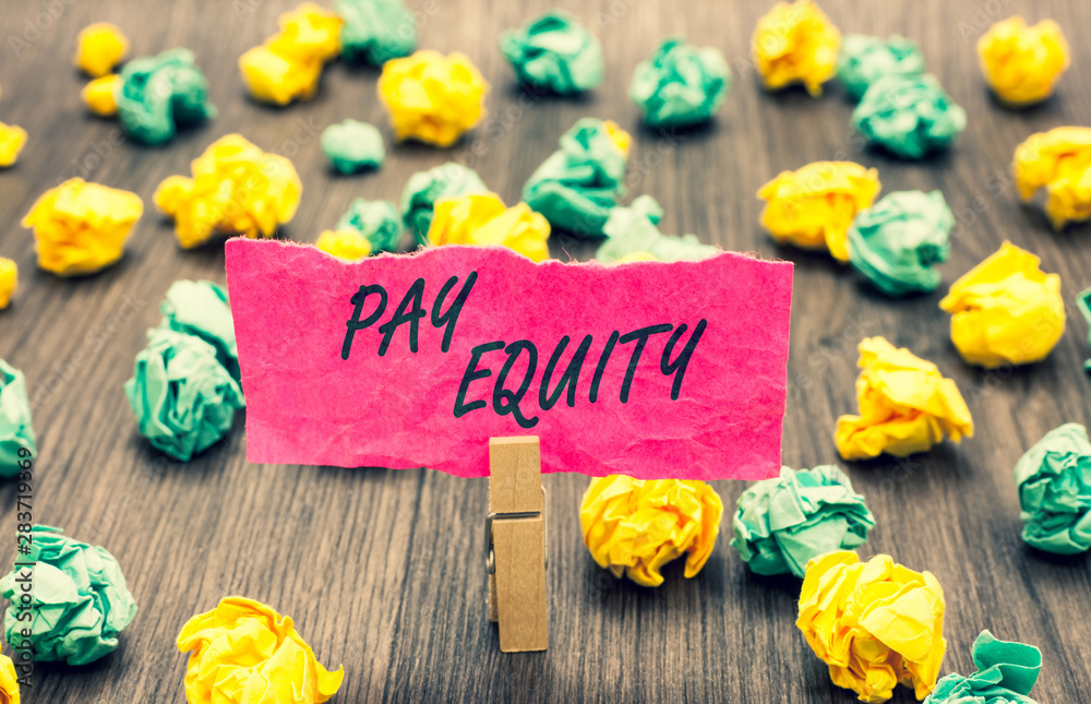 Fototapeta premium Writing note showing Pay Equity. Business photo showcasing eliminating sex and race discrimination in wage systems Clothespin holding pink note paper crumpled papers several tries