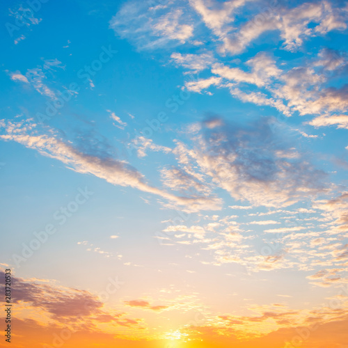 Beautiful dramatic sky at sunrise. Blue and orange colors of the sky with white clouds.