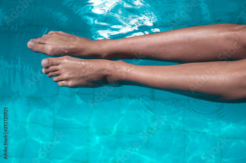 Top high angle view of female legs in the pool water