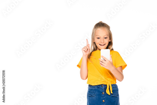cheerful child showing idea gesture while using smartphone isolated on white