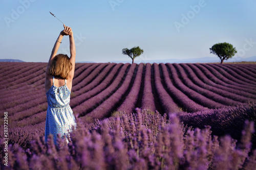 Young woman in the middle of Blooming lavender field near Valensole in Provence, France. Rows of purple flowers