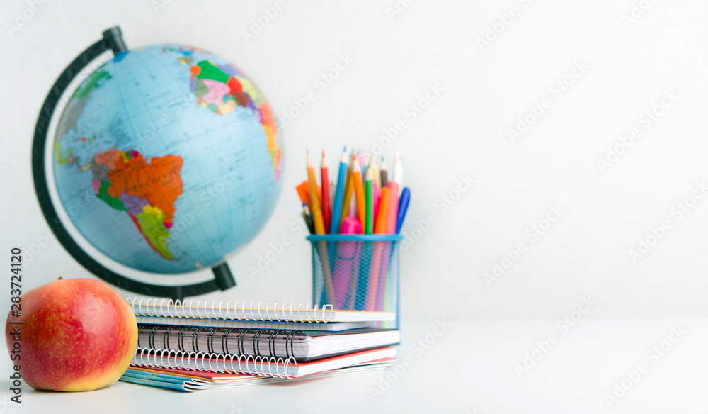 Naklejka premium World globe, apple and supplies on white background