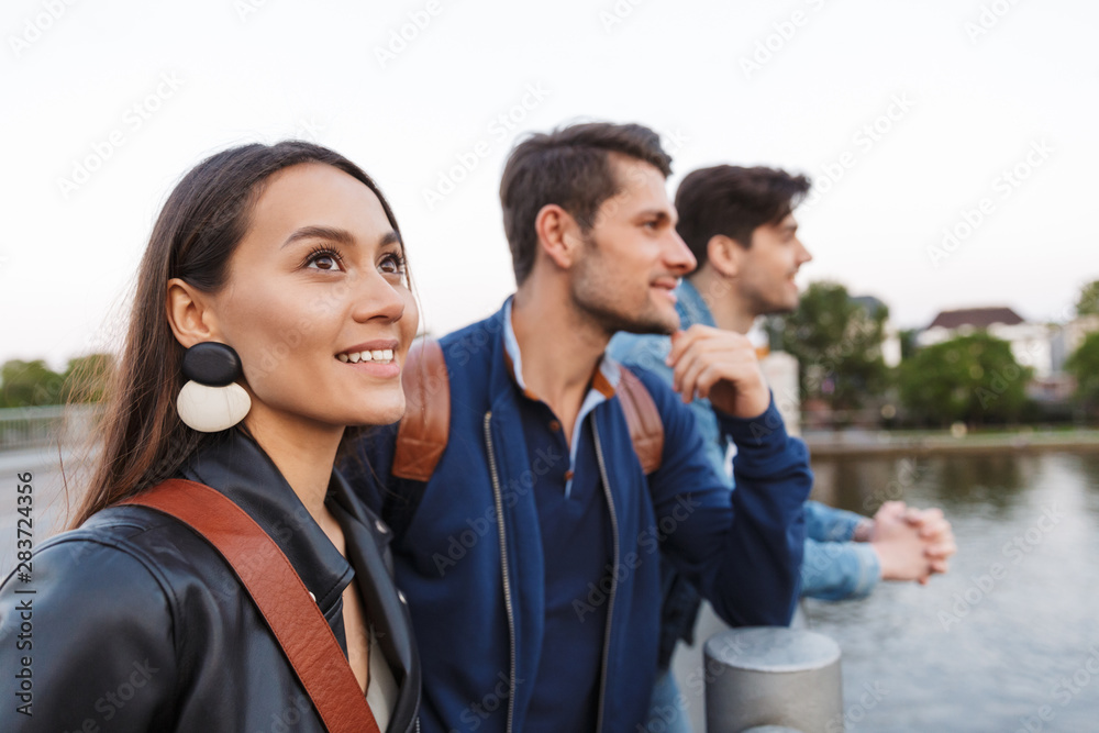 Positive optimistic happy young friends walking outdoors looking at lake. Positive optimistic happy young friends walking outdoors looking at lake.