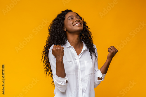 Black girl smiling and raising clenched fists in the air