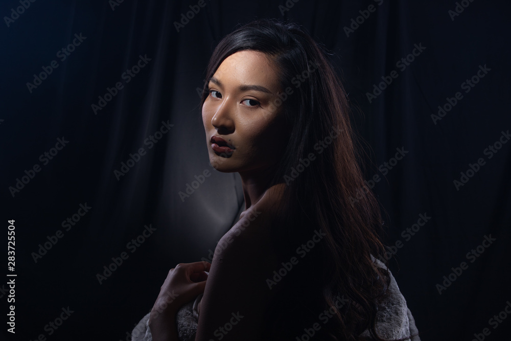 Portrait Fashion Beautiful Asian Woman make up attractive glam in fur coat and long curl black hair. Studio Lighting dark Background with smoke