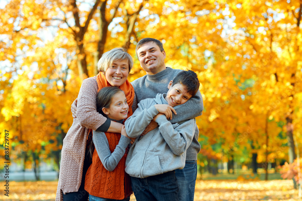 Happy family posing, playing and having fun in autumn city park. Children and parents together having a nice day. Bright sunlight and yellow leaves on trees, fall season. Happy family posing, playing and having fun in autumn city park. Children and parents together having a nice day. Bright sunlight and yellow leaves on trees, fall season.