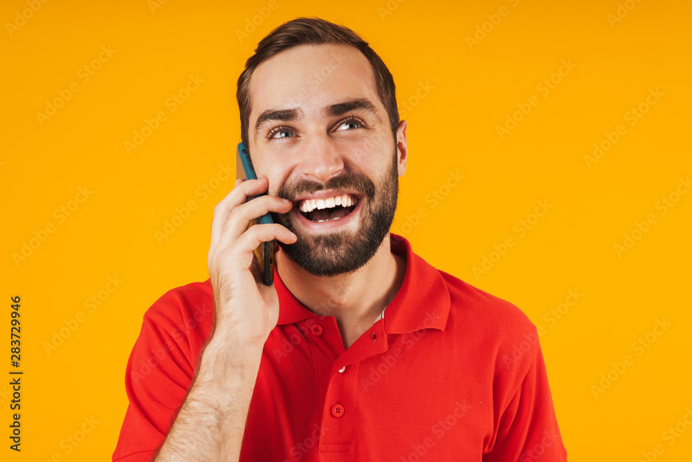 Portrait of optimistic man in red t-shirt smiling and talking on smartphone Portrait of optimistic man in red t-shirt smiling and talking on smartphone