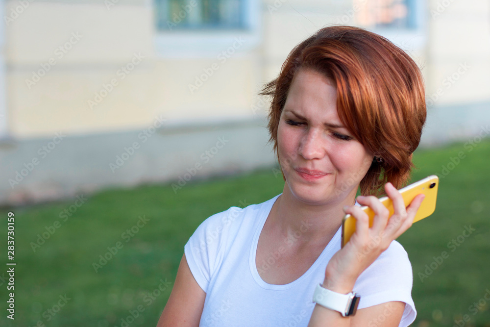 Displeased young girl annoyed by talking on the phone, looking at her smartphone with a dissatisfied look. Upset angry woman holding a cellphone. Female furious talking, remove the phone from the ear Displeased young girl annoyed by talking on the phone, looking at her smartphone with a dissatisfied look. Upset angry woman holding a cellphone. Female furious talking, remove the phone from the ear