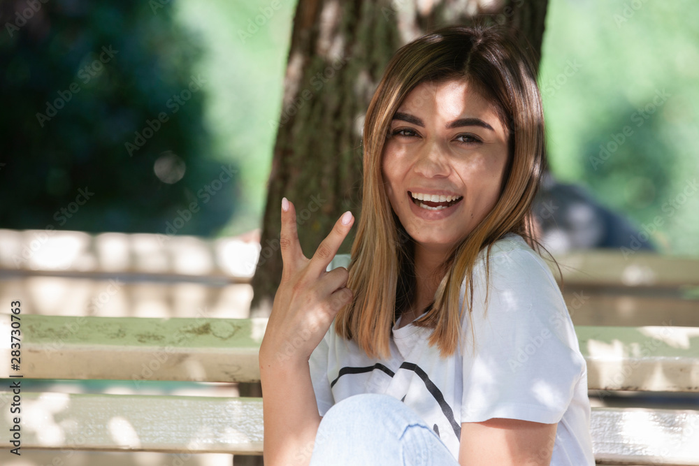 Young woman drinking coffee from paper cup. Sitting on bench in park. Young woman drinking coffee from paper cup. Sitting on bench in park.