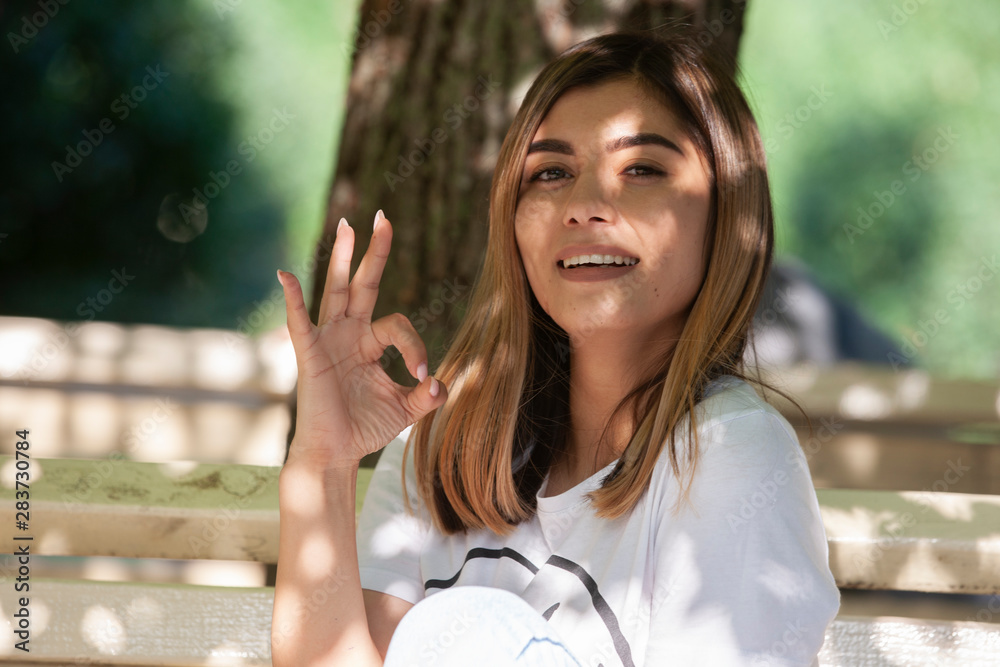 Young woman drinking coffee from paper cup. Sitting on bench in park. Young woman drinking coffee from paper cup. Sitting on bench in park.