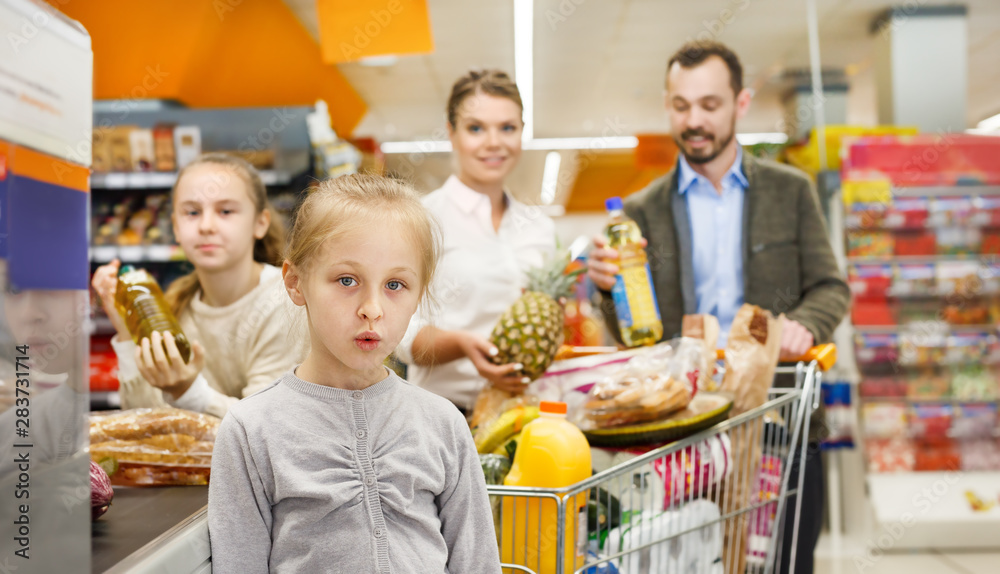 Family is standing with food near cashbox in supermarket