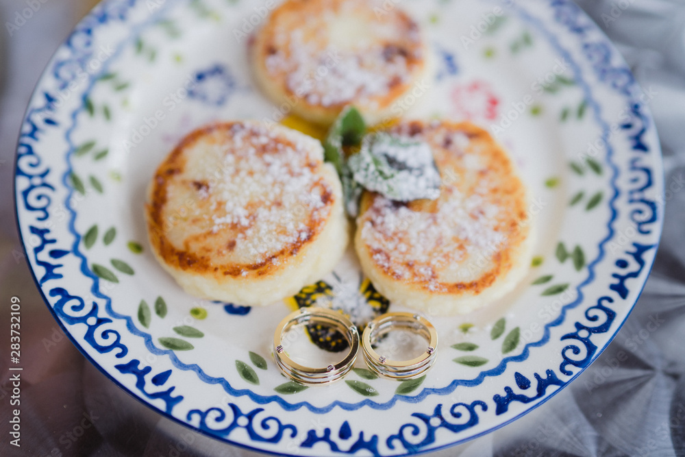 Wedding rings on a plate with tasty country cheese pancakes