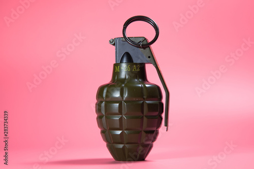 Green metal hand Grenade with round pin over When I pull out it will blow Bomb On a pink background