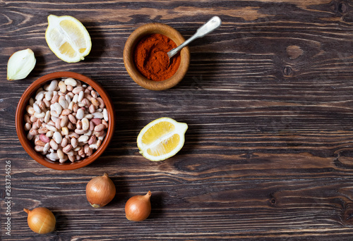Prebranac ingredients. Balkan baked beans. Serbian, Montenegrin, Bosnian, Croatian and Slovenian cuisine. Uncooked beans, onion, lemon, paprika powder. Wooden background. Top view. Space for text
