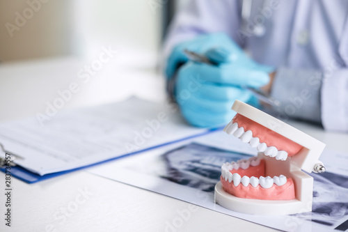 Male doctor or dentist working with patient tooth x-ray film, model and equipment used in the treatment and analysis teeth disease of dental and dentistry at workplace photo